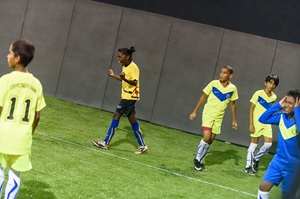 Kids with blue and green shirts playing football on a field